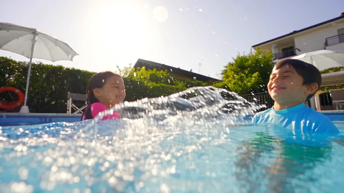 Due bambini che ridono e si schizzano l'acqua nella piscina del residence