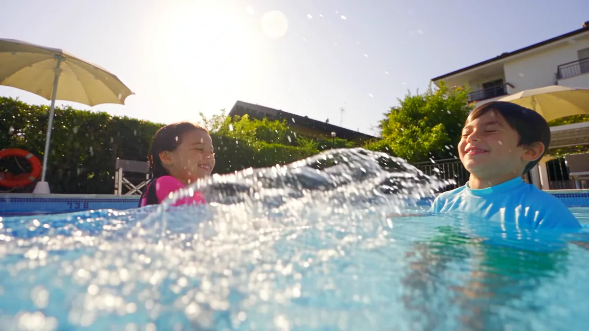 Due bambini che ridono e si schizzano l'acqua nella piscina del residence