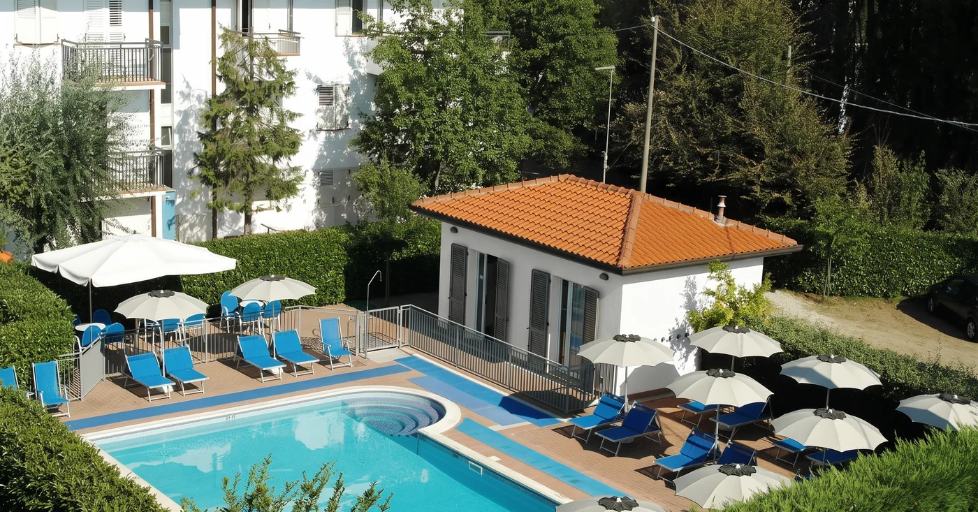 La piscina esterna del Residence Il Villaggio a Bellaria Igea Marina, con lettini blu e ombrelloni