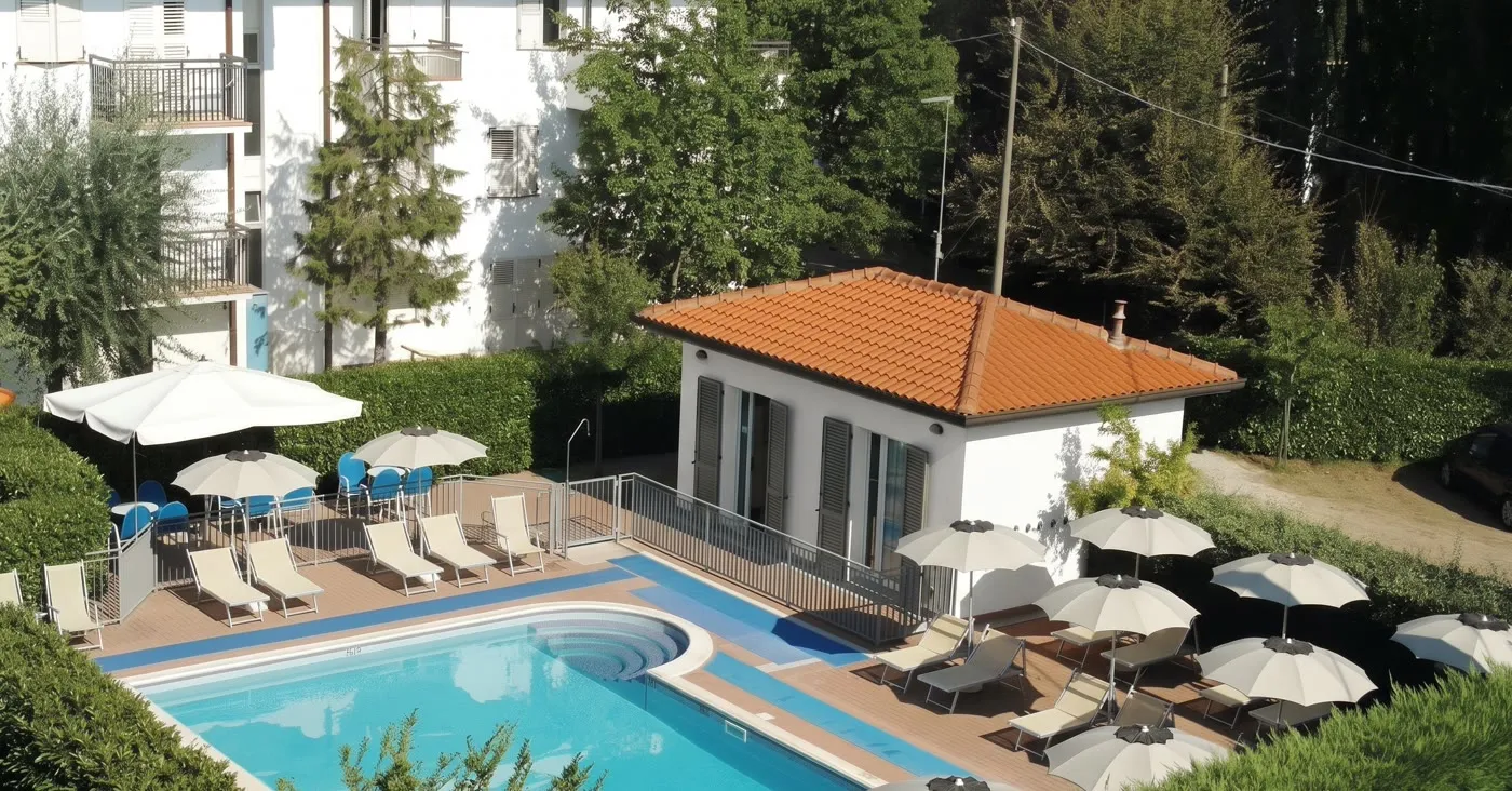 La piscina esterna del Residence Il Villaggio a Bellaria Igea Marina, con lettini blu e ombrelloni