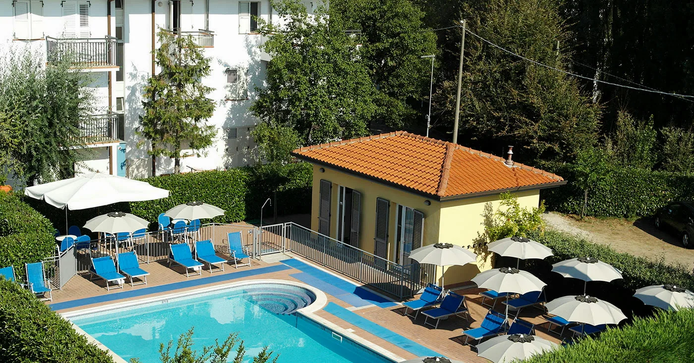 La piscina esterna del Residence Il Villaggio a Bellaria Igea Marina, con lettini blu e ombrelloni