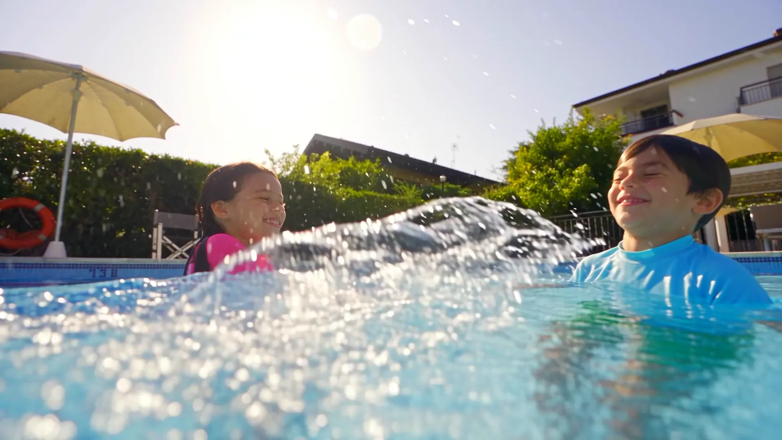 Due bambini che ridono e si schizzano l&rsquo;acqua in piscina