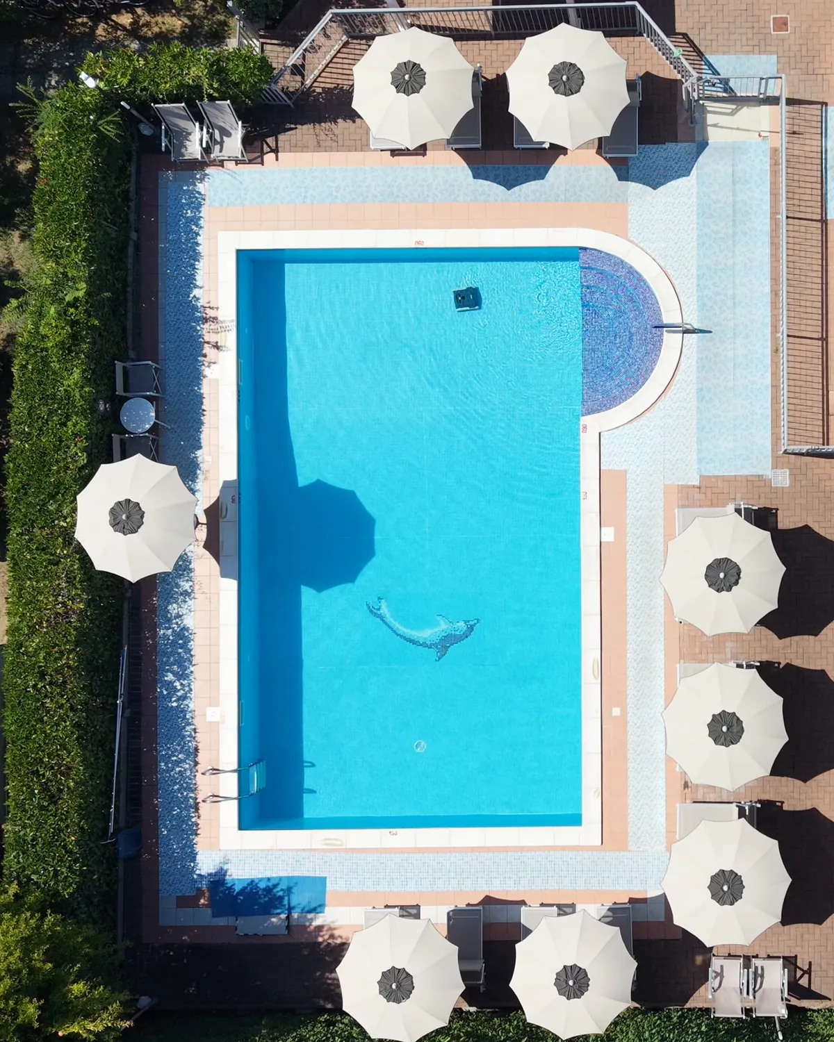 La piscina vista dal drone: la scalinata tonda in mosaico, la parte lunga e gli ombrelloni intorno
